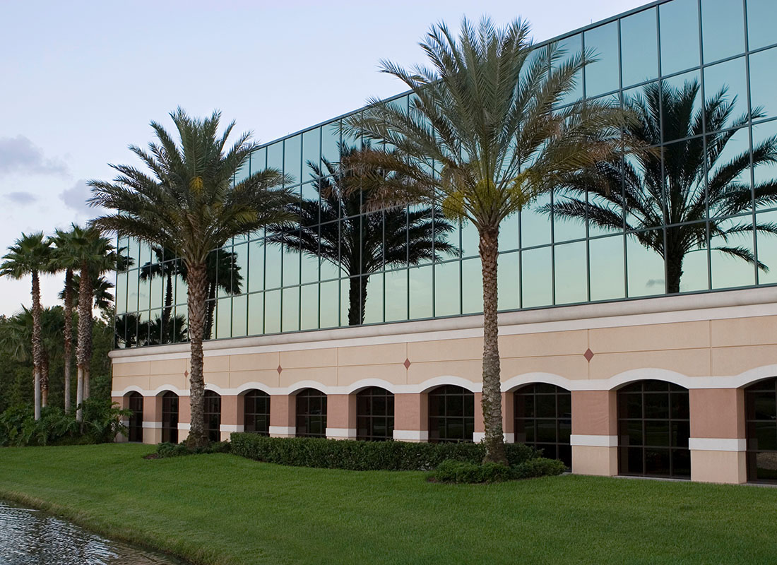 Business Insurance - View of a Modern Commercial Building with Palm Trees in the Front and a Bright Green Lawn at Sunset