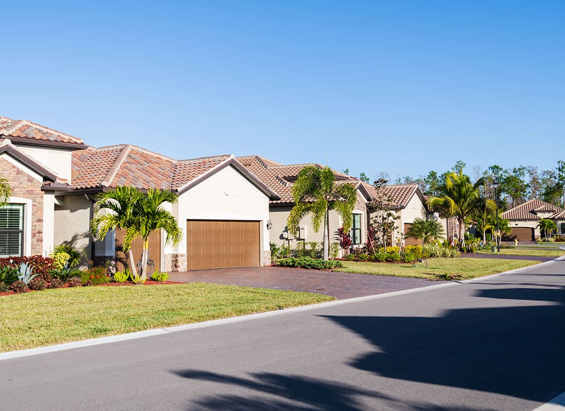 Insurance Solutions - Quiet Residential Neighborhood in Florida with Single Story Homes with Palm Trees and Garages Against a Bright Blue Sky